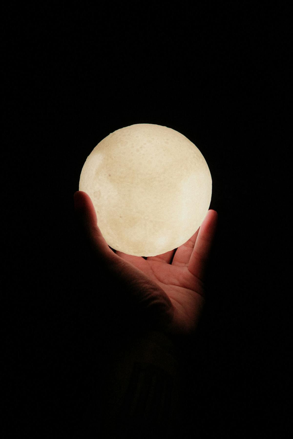 Hands holding a glowing 3D moon lamp